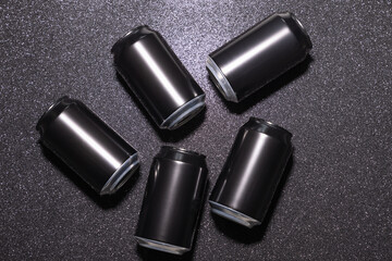 Black aluminium soda cans on a black background with sparkles, view from above