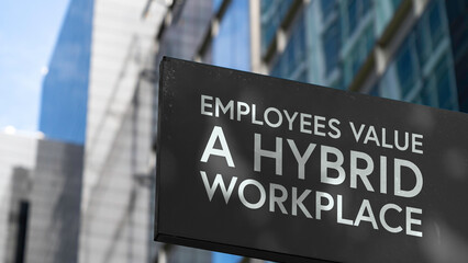 Employees value a hybrid workplace on a black city-center sign in front of a modern office...