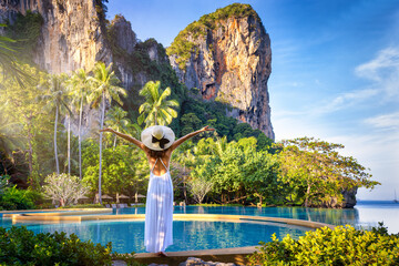 A summer travel concept with a woman in a white dress looking at the tropical paradise beach of Railay, Krabi, Thailand - 567986390