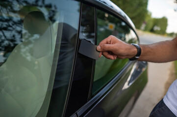 A man holds an electronic key card from a black electric car. 