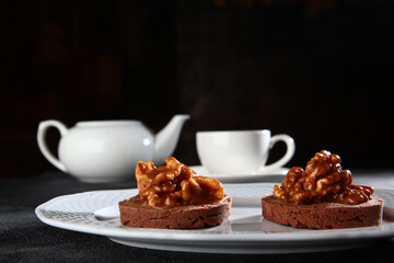 Chocolate brownie with walnuts. Breakfast concept. The kettle is out of focus.Black background.