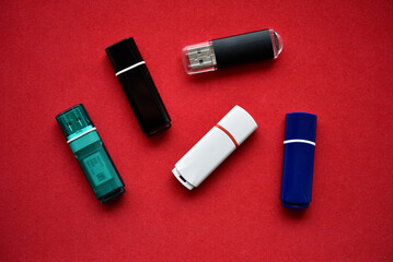 Colored flash drives on a red background. Storage of information. Flash drives in a pile.