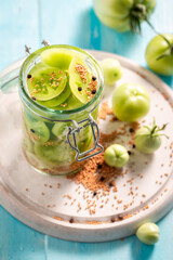 Healthy and tasty pickled green tomatoes with allspice and mustard.