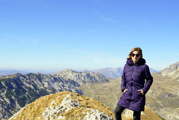 A young woman on a hiking tour poses while climbing to the top of a mountain. Active holiday in Montenegro - a trip to Durmitor National Park.