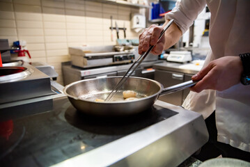 man chef cooking fried shrimp in frying pan on kitchen
