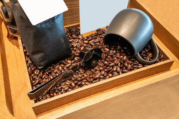 Blank coffee packaging on a wooden table, with metal spoon, coffee seeds bowl and black ceramic cup, on a wooden background.