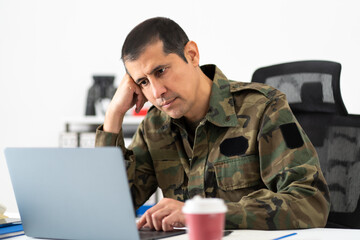 Mid adult male soldier with a stress headache feeling tired, pain and stressed while working on a...