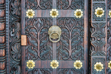 Traditional arab zanzibar wooden door and doorway ornately carved and decorated with brass fittings - obrazy, fototapety, plakaty