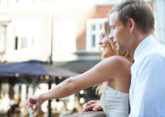 Wedding couple, city and love of happy people together on a bridge with a smile and care. Loving celebration, date and pointing woman with husband celebrating marriage, connection and anniversary