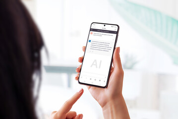 Woman holding a smart phone and using a chat bot app to ask questions about a smart watch. Showcases the use of AI language models to provide accessible and interactive information on the go