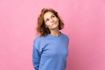 Fototapeta premium Young Georgian woman isolated on pink background and looking up