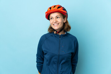 Young cyclist woman isolated on blue background thinking an idea while looking up