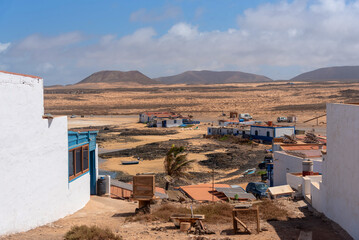 
Pueblo de Majanicho con pequeñas casas coloridas en medio de un paisaje desértico y montañas volcánicas al fondo en la turística Fuerteventura en un día soleado en las Islas Canarias.