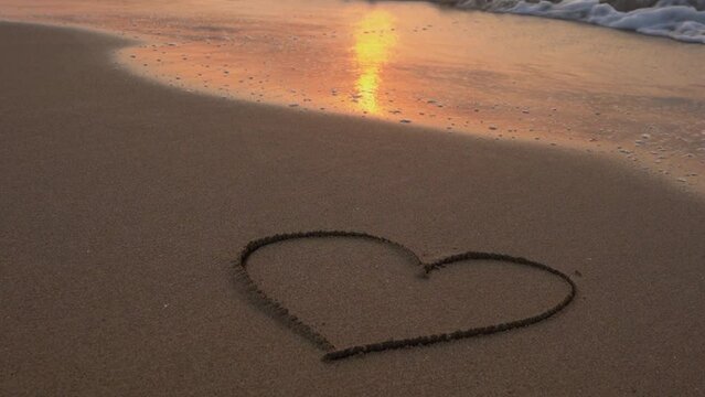 the drawn heart on the sand is washed away by the wave at sunset. Symbol of romantic love on a tropical seashore at sunset. golden sand nature concept valentine's day love confession rest Sicily