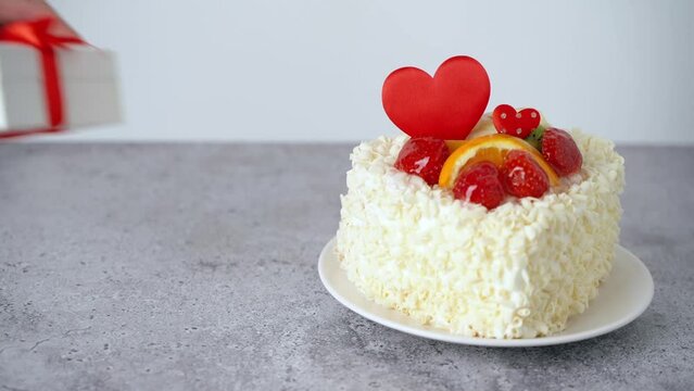 Valentine's Day cake, roses flowers, gift with heart shape and fruits, strawberries. Birthday Cake for celebration. Valentine's Day and love concept. Present with love.