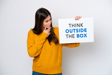 Young Brazilian woman isolated on white background holding a placard with text Think Outside The Box and thinking