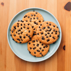 pile of Chocolate chip cookies on light blue plate, on wooden surface, flat lay
