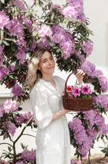 Romantic girl with a basket in the rhododendron bushes.