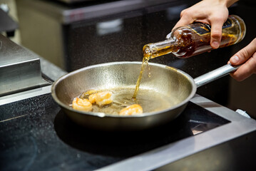 man chef cooking fried shrimp in frying pan on kitchen