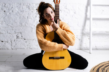 portrait of a beautiful young woman sitting with a guitar