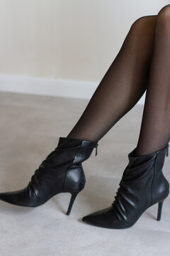 Women's slender legs in tights and boots in a beautiful modern interior