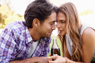 Young couple drinking soda together in park, summer holiday or valentines date for outdoor romance and love. Relax, happy people or woman with partner sharing a cola bottle and straw in garden picnic