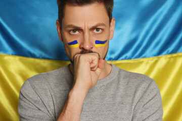 Angry man with face paint near Ukrainian flag