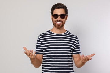 Portrait of smiling bearded man with stylish sunglasses on grey background