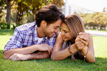 Couple, love or forehead touch on grass date, nature park or garden bonding on valentines day, romance or anniversary trust. Smile, happy woman or man lying in relax environment or partnership picnic