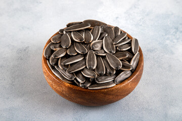 Black sunflower seeds in a bowl on bright background