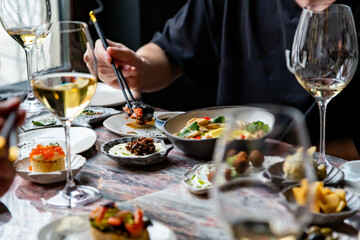 glass with wine and wine snack set, cheese, meat, vegetables and other appetizers on table