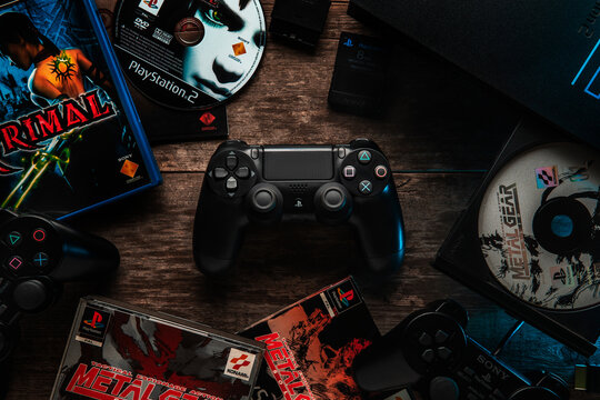 Odessa, Ukraine - April 12, 2019: The DualShock4 Wireless Controller for PlayStation4. Gamepad black for PS4 on a vintage wooden table among the PS2 console and games for it.