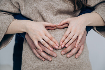 The appearance of the firstborn. First birth. Pregnancy. Hands rest on the pregnant belly