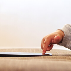 Child's finger pressing, scrolling, tapping on mobile phone screen. Little child learns to use new technologies. Baby pressing with finger on phone touch screen, close-up and soft focus.