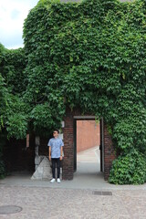 Fototapeta na wymiar Man standing by small door of castle garden with beautiful green leaves wall