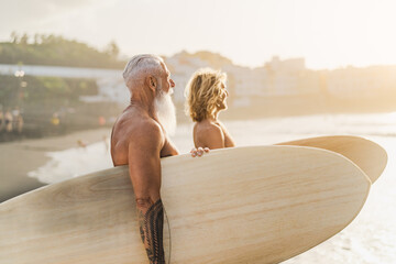 Happy surfers with different ages having fun surfing on tropical beach - Extreme sport lifestyle...