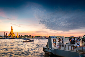 Naklejka premium Tourists photograph Bangkok's Wat Arun,from a riverside viewpoint,at sunset.
