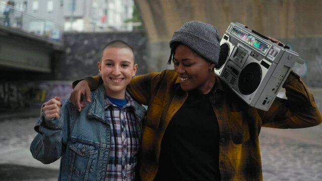 Happy multiracial girls having fun dancing while listening to music with vintage boombox stereo