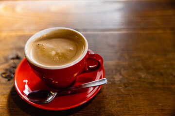 Cafe latte in a red cup on a wooden desk