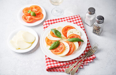 Caprese salad with tomatoes, mazzarella cheese and basil leaves in a plate