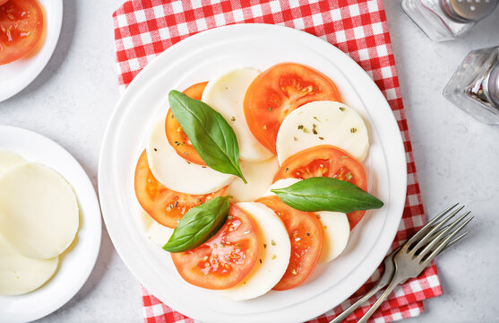Caprese salad with tomatoes, mazzarella cheese and basil leaves in a plate
