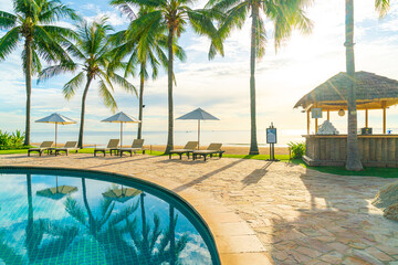 Beautiful luxury umbrella and chair around outdoor swimming pool in hotel and resort with coconut...