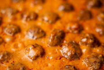 Cooking homemade meatballs in a frying pan in a sauce of tomatoes and sour cream. Close-up macro. Food background.