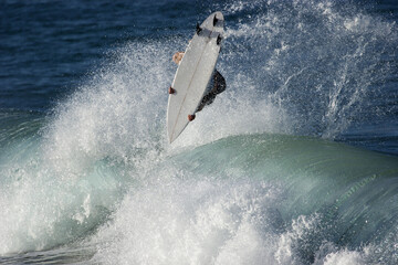 Obraz premium A surfer executes a radical aerial move on as he surfs a wave in the ocean.