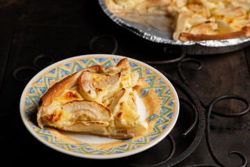 A piece of apple pie on a plate on a dark background. Sliced baked in apple dough. Charlotte.