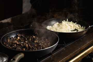Frying mushrooms in a pan. Finely chopped champignons are cooked. Steam is coming.