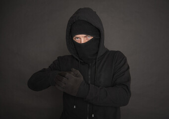 Unrecognizable man in the black hoody with hood wearing balaclava mask holding his fists near chest