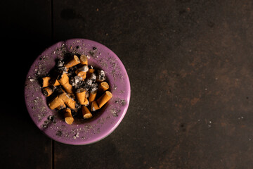 Ashtray with many cigarette butts on a dark background. The concept of a bad habit of smoking. Place for text.