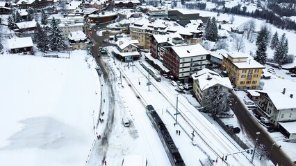 Train is arriving to Grindelwald Train Station in Switzerland aerial drone video on snowy day in winter time