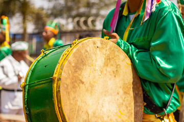 Detalhe de um folião vestido de verde, tocando bumbo durante as Congadas, festa religiosa típica...